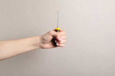 Photo of Woman holding screwdriver on grey background, closeup