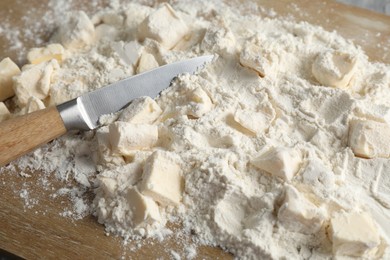 Photo of Making shortcrust pastry. Flour, butter and knife on wooden board, closeup