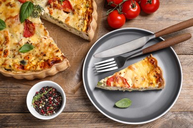 Photo of Tasty quiche with tomatoes, basil and cheese served on wooden table, flat lay