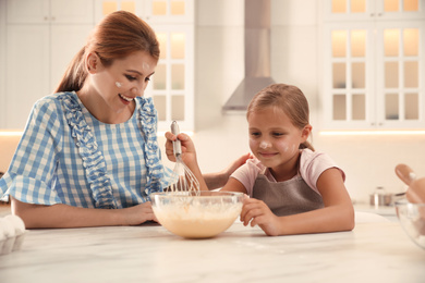 Photo of Mother and daughter making dough together in kitchen