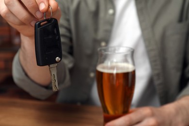 Photo of Man with glass of alcoholic drink holding car key, closeup. Don't drink and drive concept