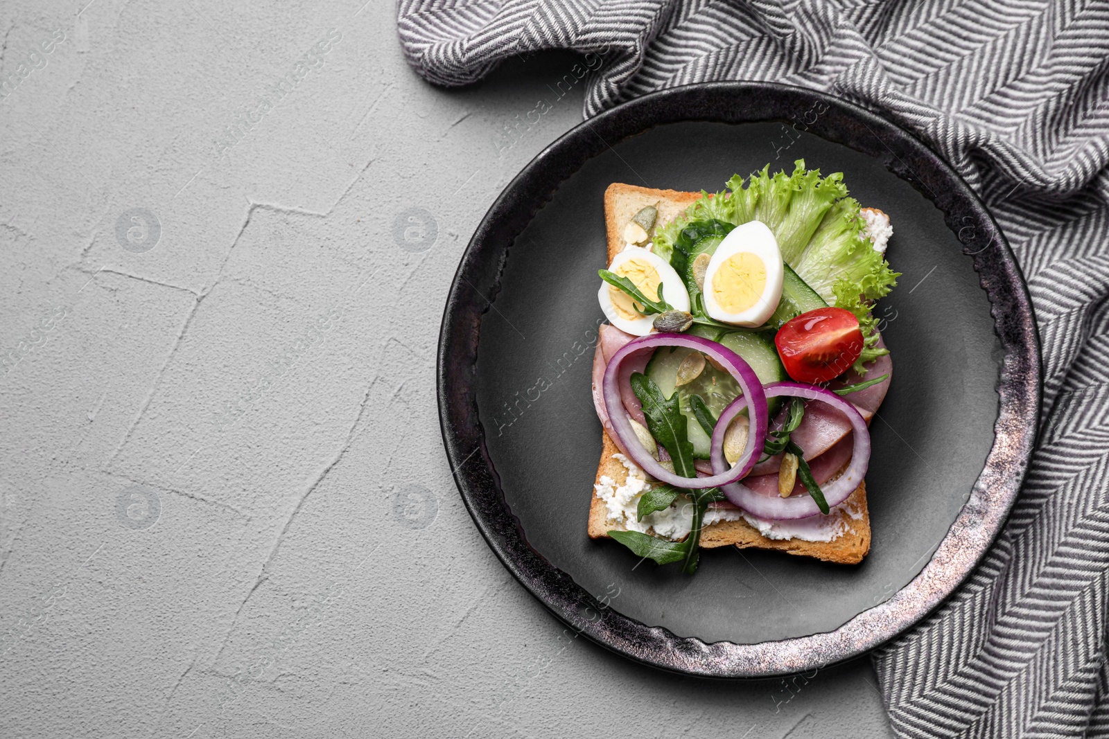 Photo of Tasty sandwich with ham and quail eggs served on grey table, flat lay. Space for text