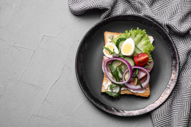 Tasty sandwich with ham and quail eggs served on grey table, flat lay. Space for text