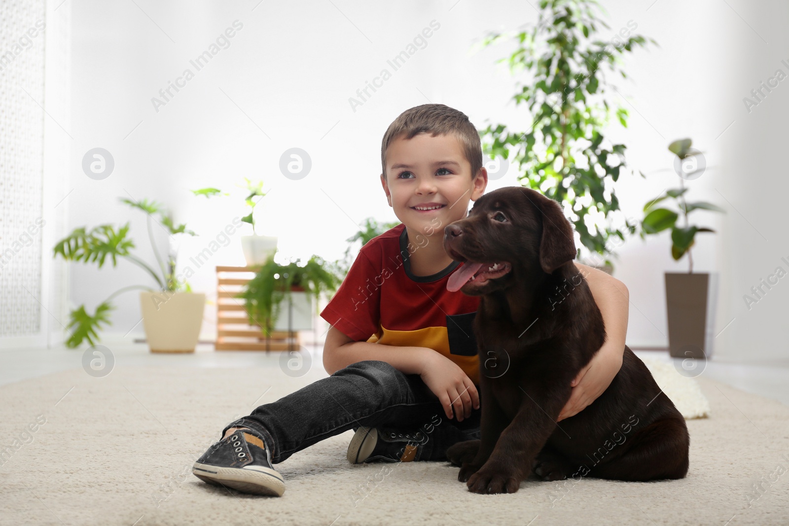 Photo of Little boy with puppy on floor at home. Friendly dog