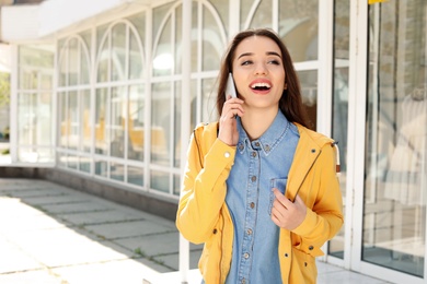 Photo of Young woman talking by phone outdoors on sunny day