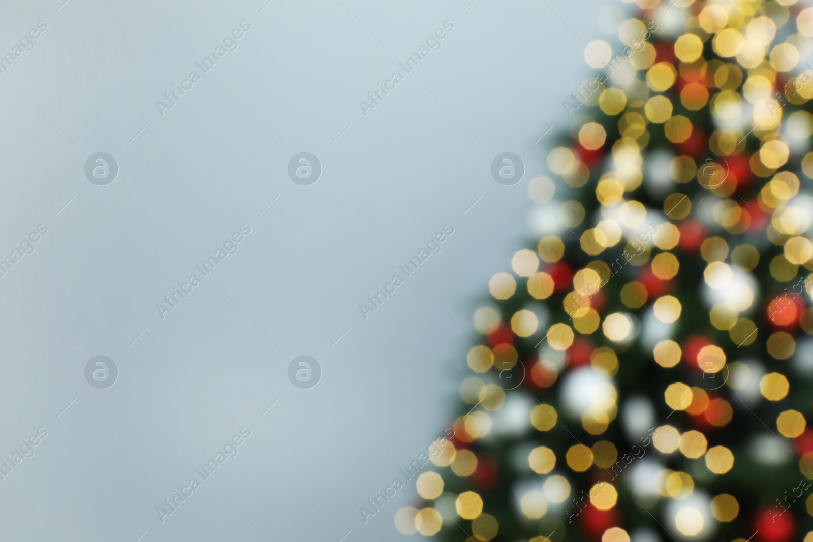 Photo of Blurred view of beautifully decorated Christmas tree on grey background, space for text