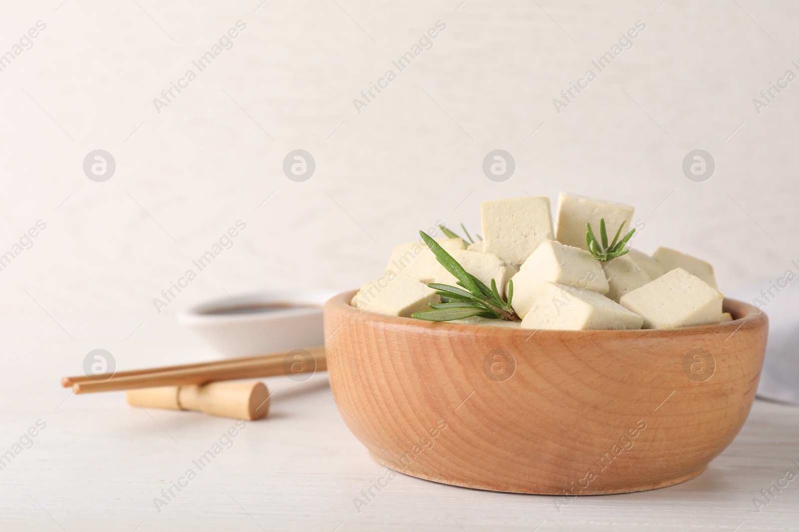 Photo of Delicious tofu with rosemary served on white wooden table. Space for text