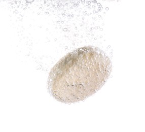 Effervescent pill dissolving in water on white background, closeup