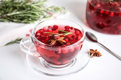 Photo of Tasty hot cranberry tea with rosemary and anise on white table