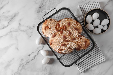 Photo of Delicious Italian Easter dove cake (Colomba di Pasqua) and decorative eggs on white marble table, flat lay. Space for text