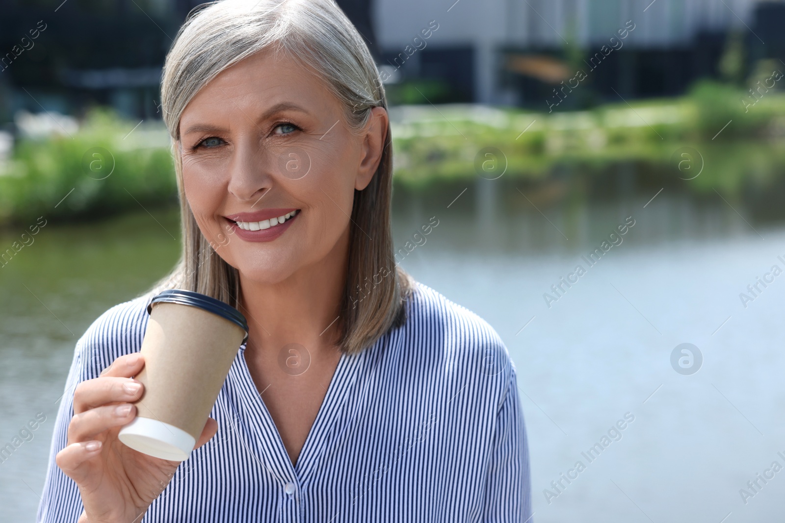 Photo of Portrait of happy senior woman with paper cup of coffee outdoors, space for text
