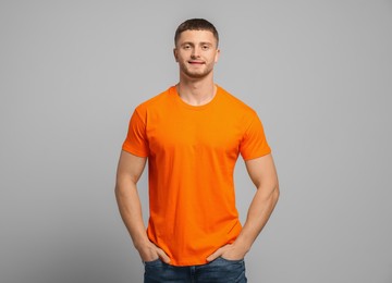 Man wearing orange t-shirt on light grey background. Mockup for design