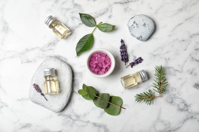 Photo of Different essential oils and ingredients on marble background, flat lay