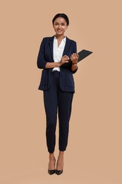Photo of Beautiful secretary with clipboard and pen on beige background