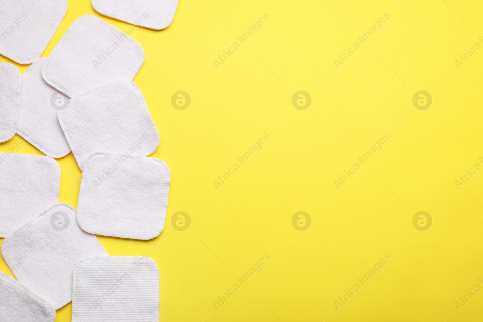 Photo of Soft clean cotton pads on yellow background, flat lay. Space for text