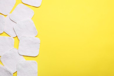 Soft clean cotton pads on yellow background, flat lay. Space for text