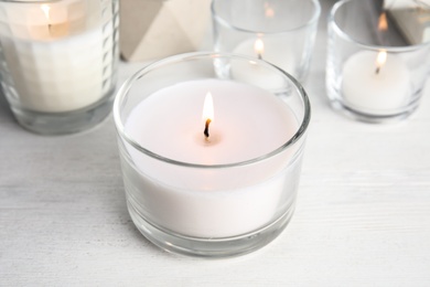 Burning aromatic candle in holder on table