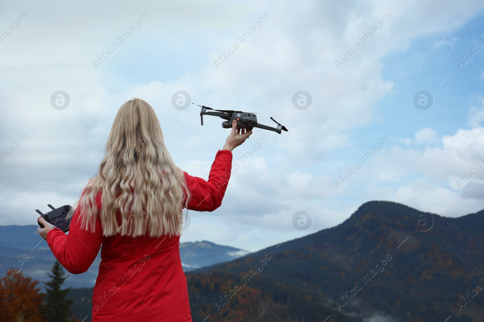 Photo of Young woman with modern drone in mountains, back view. Space for text