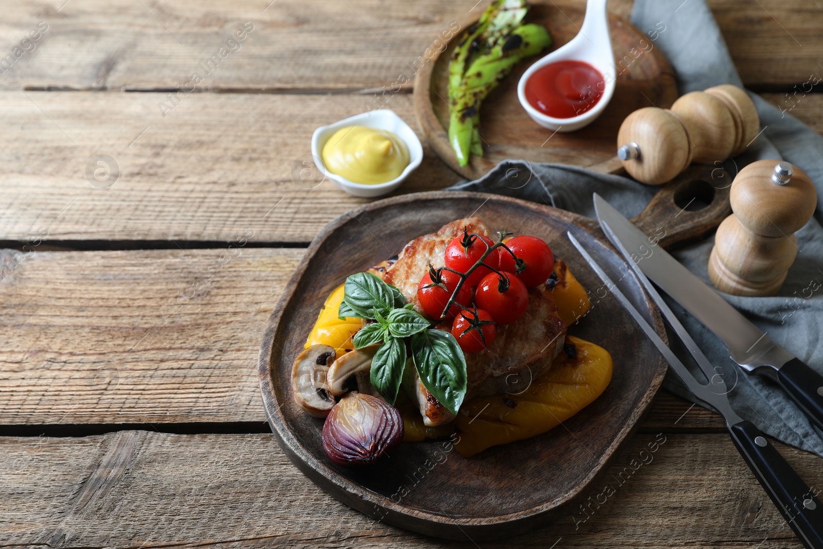 Photo of Delicious grilled meat and vegetables served with sauces on wooden table. Space for text