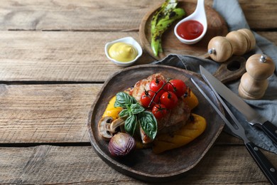 Photo of Delicious grilled meat and vegetables served with sauces on wooden table. Space for text