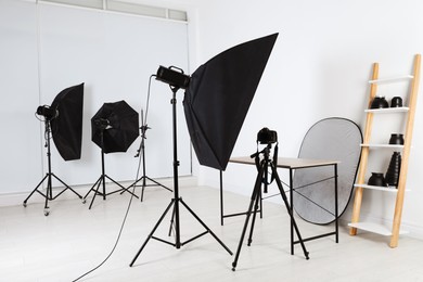Empty table in front of camera and professional lighting equipment indoors. Photo studio set