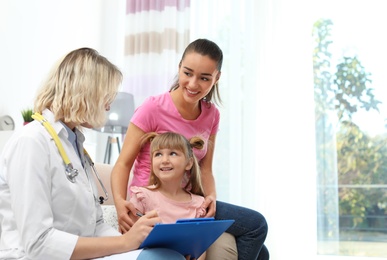 Photo of Children's doctor visiting little girl at home. Space for text