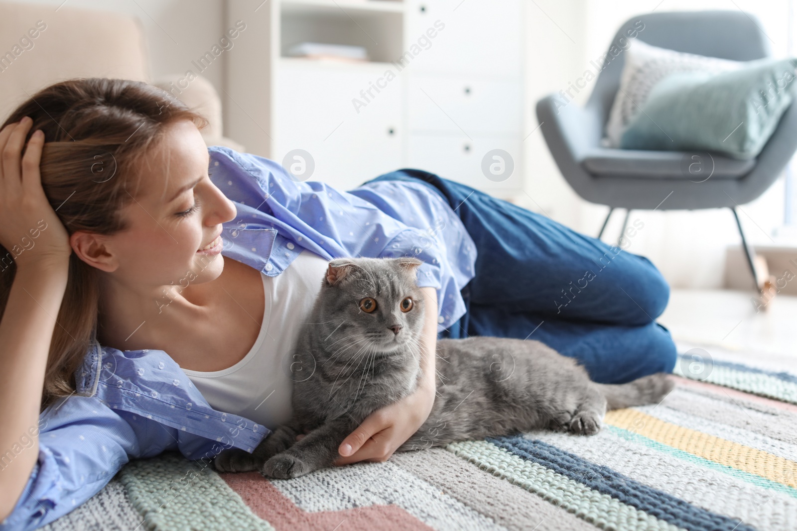 Photo of Young woman with her cute pet cat on floor at home