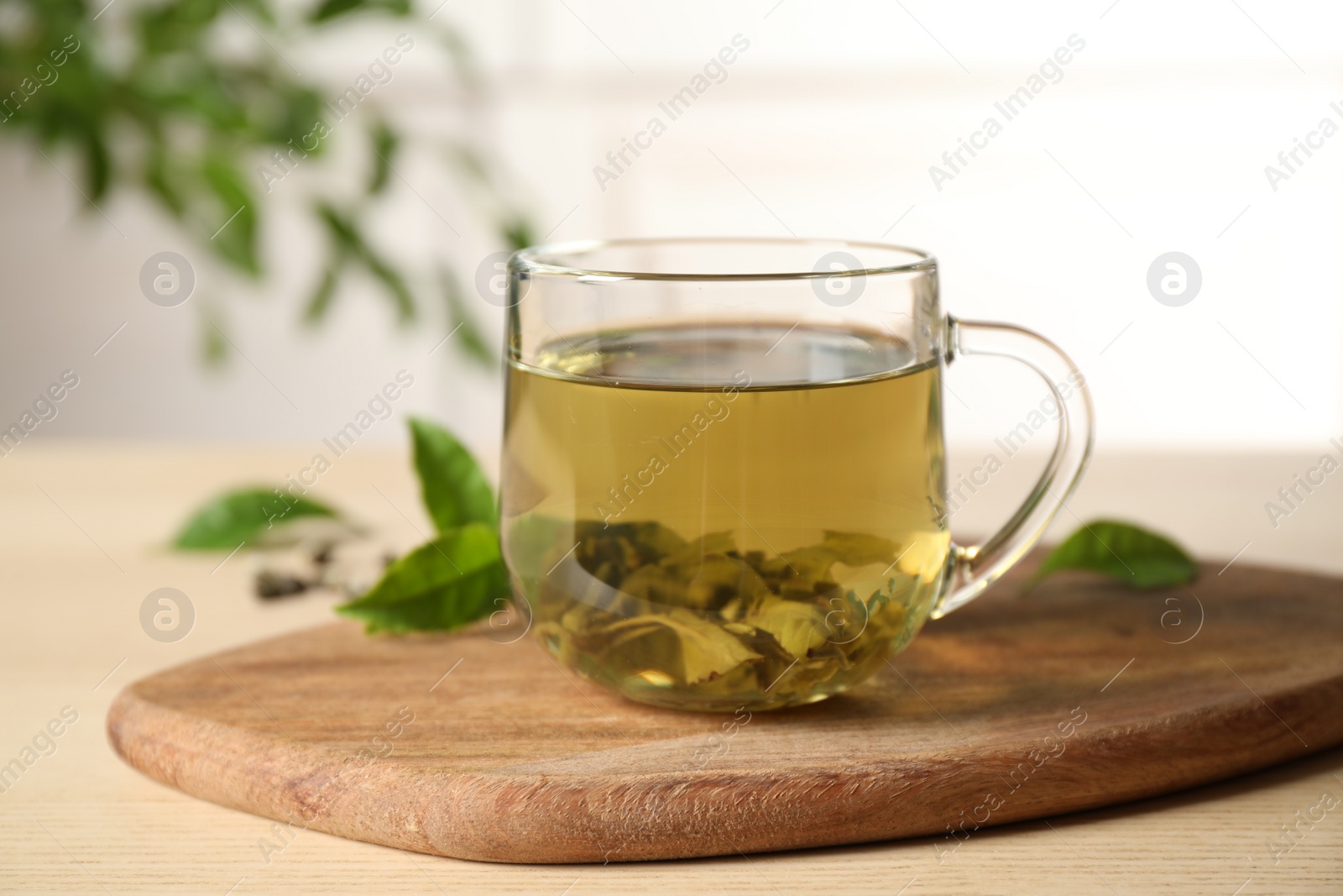 Photo of Tasty hot green tea in cup on wooden table, closeup