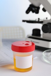 Photo of Container with urine sample for analysis on white table in laboratory