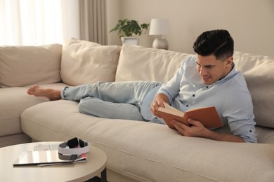 Man reading book on sofa in living room