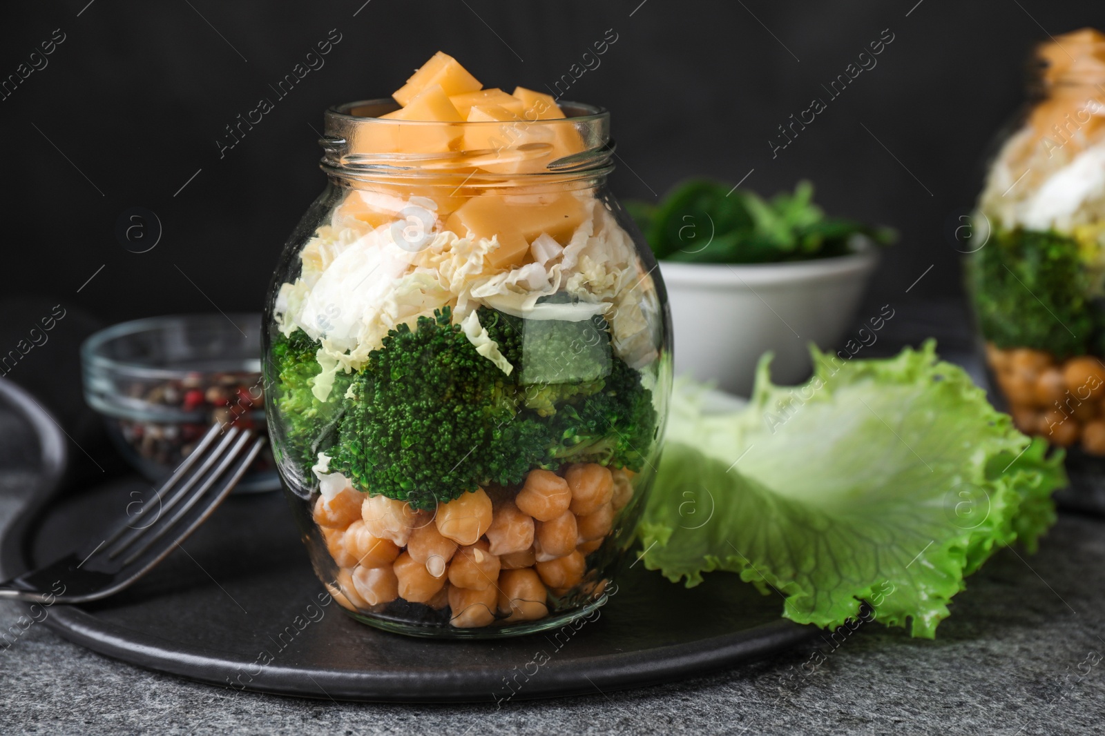 Photo of Healthy salad in glass jar on grey table