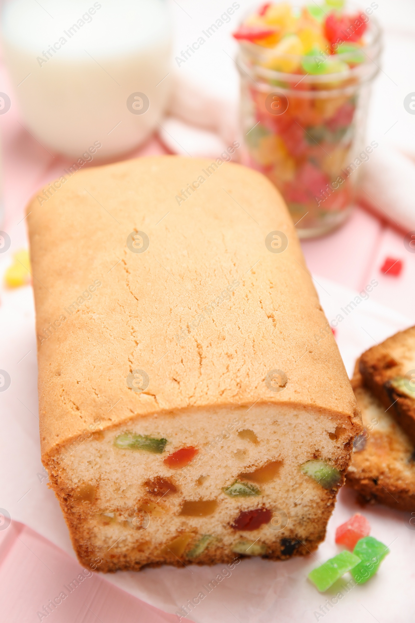 Photo of Delicious cake with candied fruits on pink table, closeup