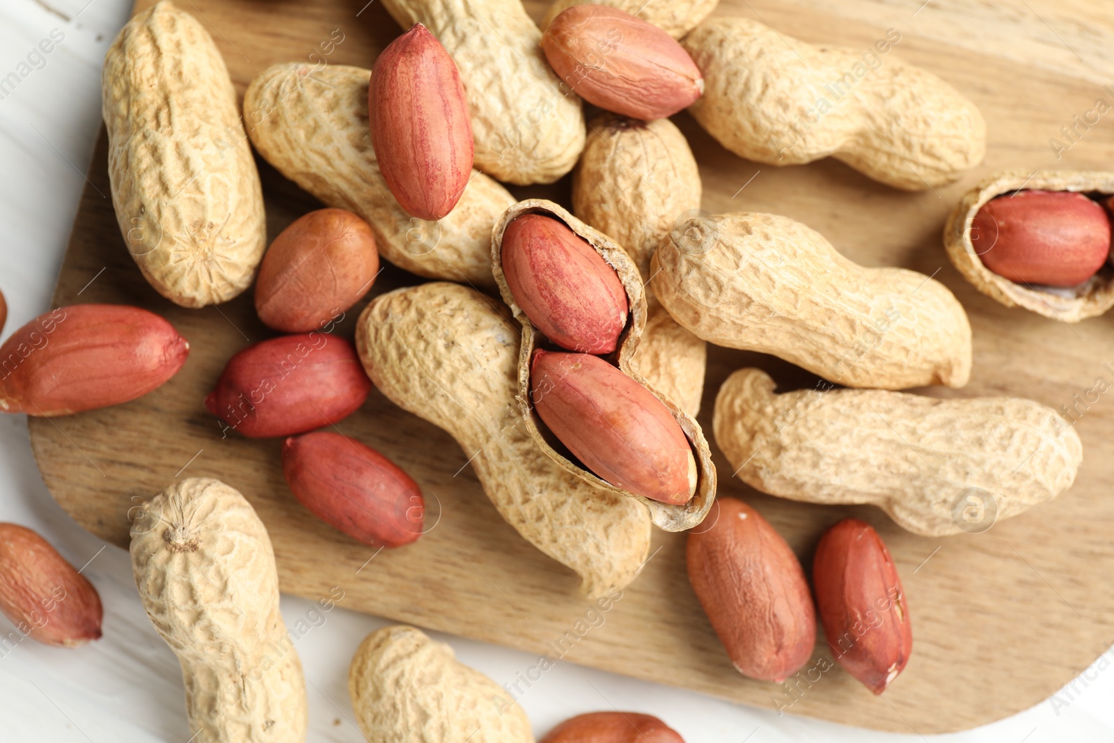 Photo of Fresh unpeeled peanuts on white table, top view