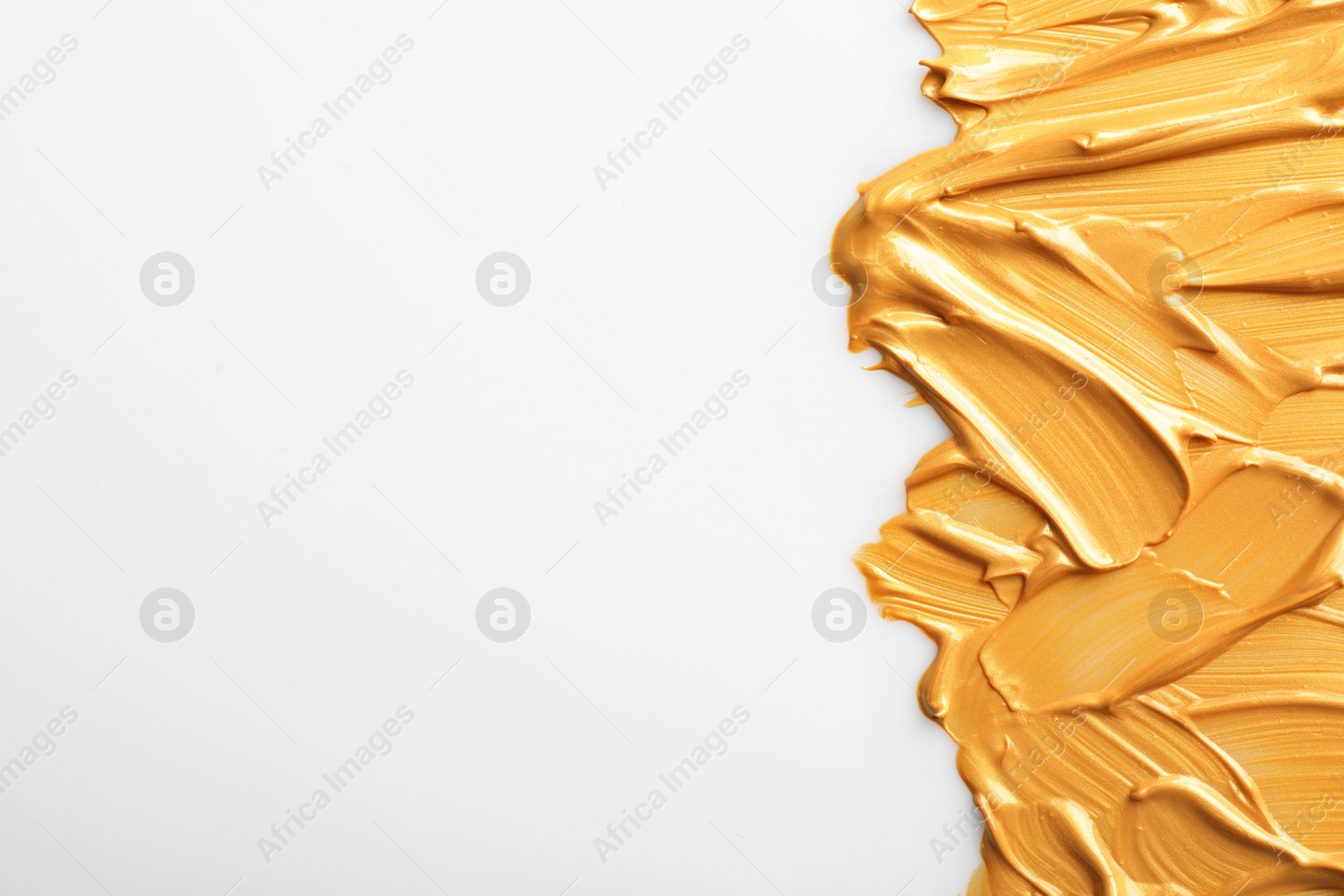 Photo of Strokes of gold paint isolated on white, top view