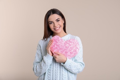 Photo of Portrait of woman with decorative heart shaped pillow on color background
