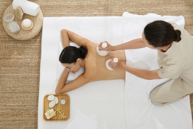 Photo of Young woman receiving herbal bag massage in spa salon, top view
