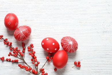 Photo of Flat lay composition with painted Easter eggs on wooden table, space for text