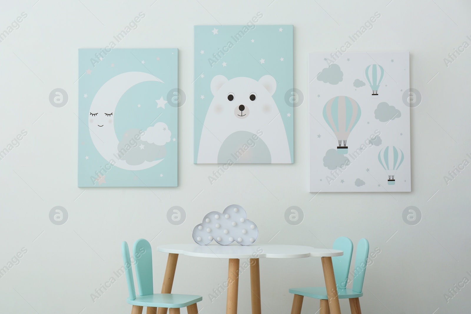 Photo of Adorable wall art, table and chairs with bunny ears in children's room interior