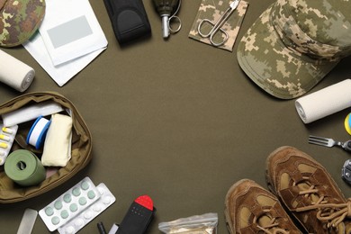 Photo of Flat lay composition with first aid kit and military uniform on khaki background. Space for text