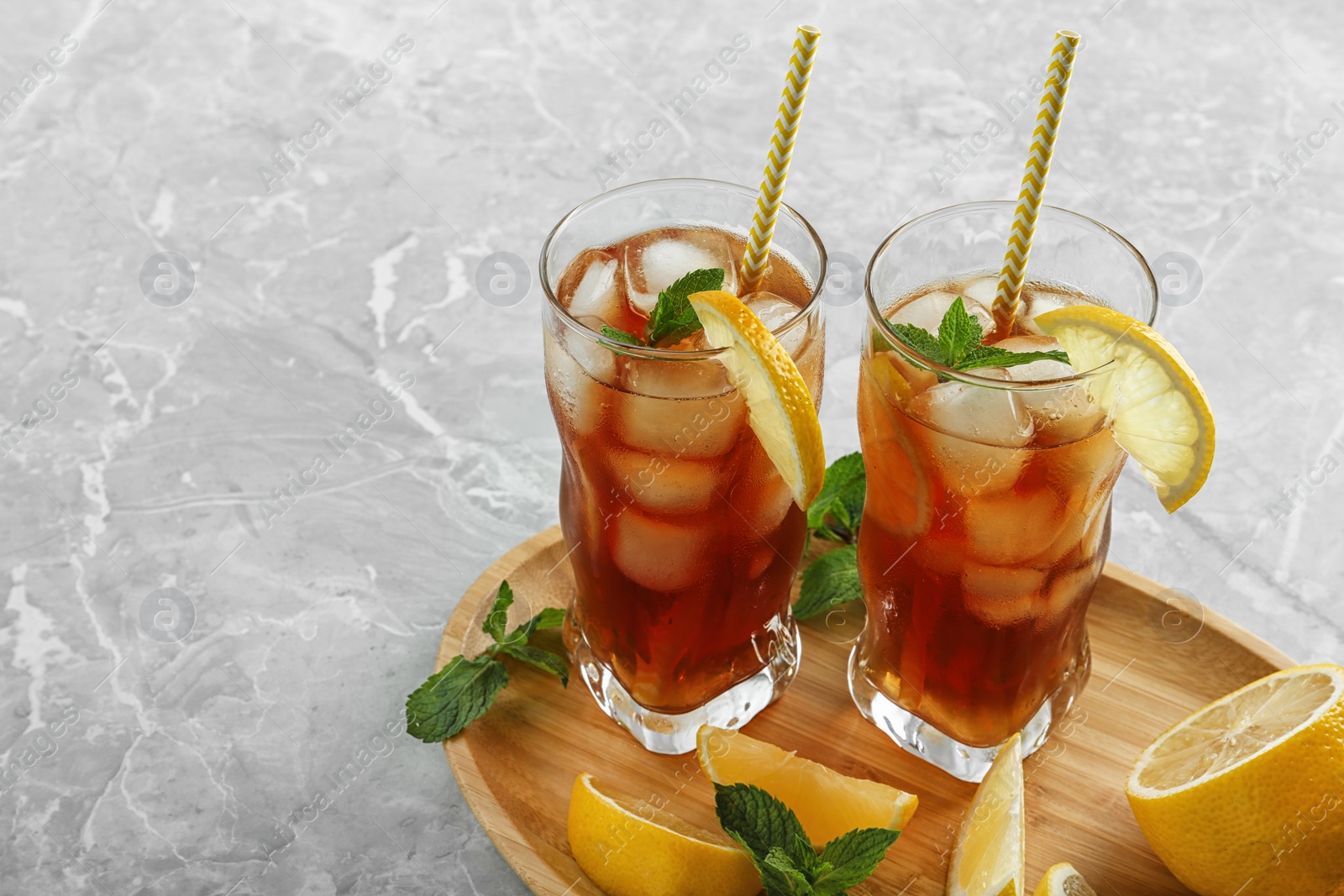 Photo of Glasses of delicious iced tea on marble table. Space for text