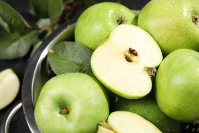 Photo of Ripe green apples with water drops in colander on table, closeup