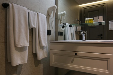 Rack with soft towels mounted on wall in bathroom