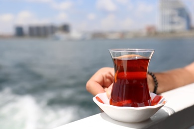 Photo of Man with glass of tea and blurred sea on background, closeup