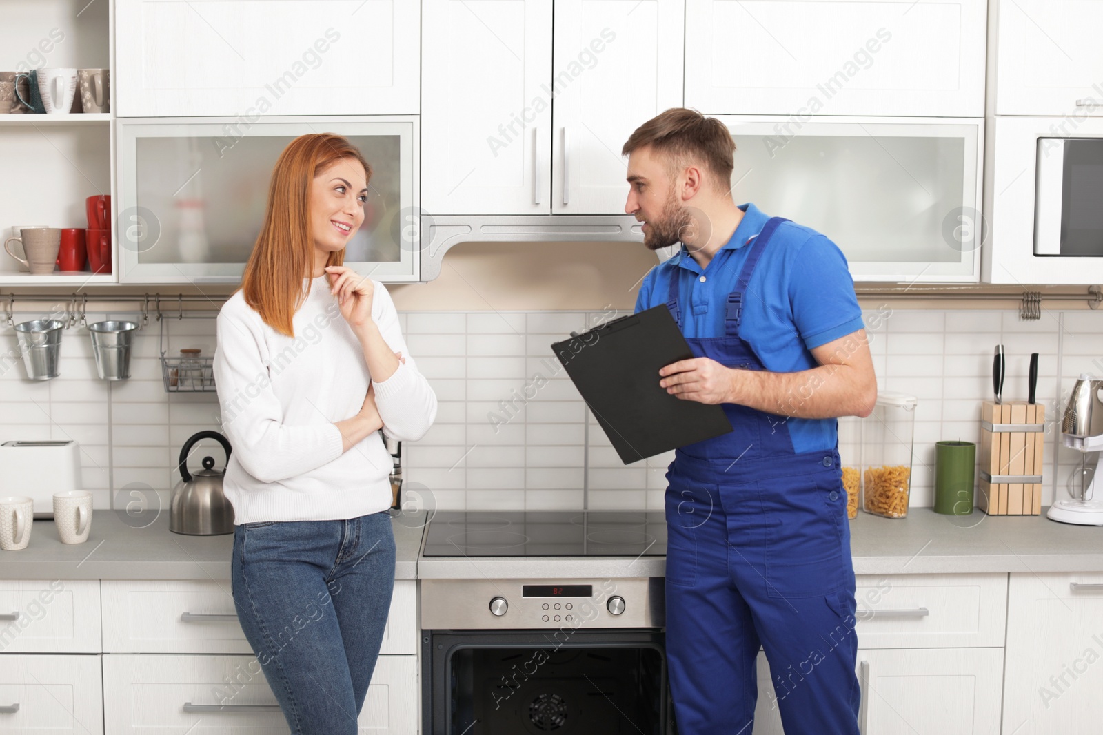 Photo of Housewife with repairman near modern oven in kitchen