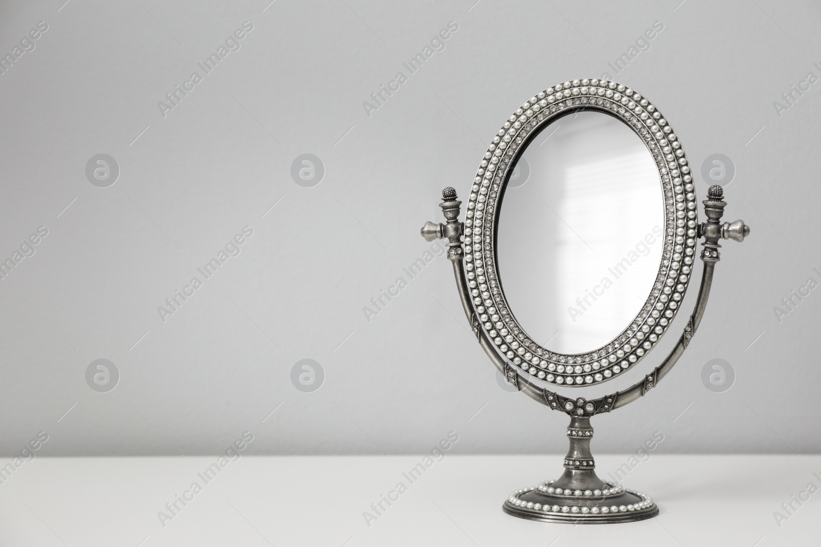 Photo of Stylish round mirror on table near white wall, space for text