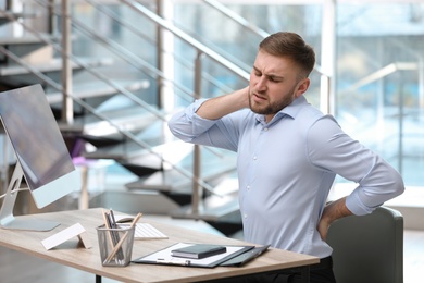 Businessman suffering from back pain at workplace