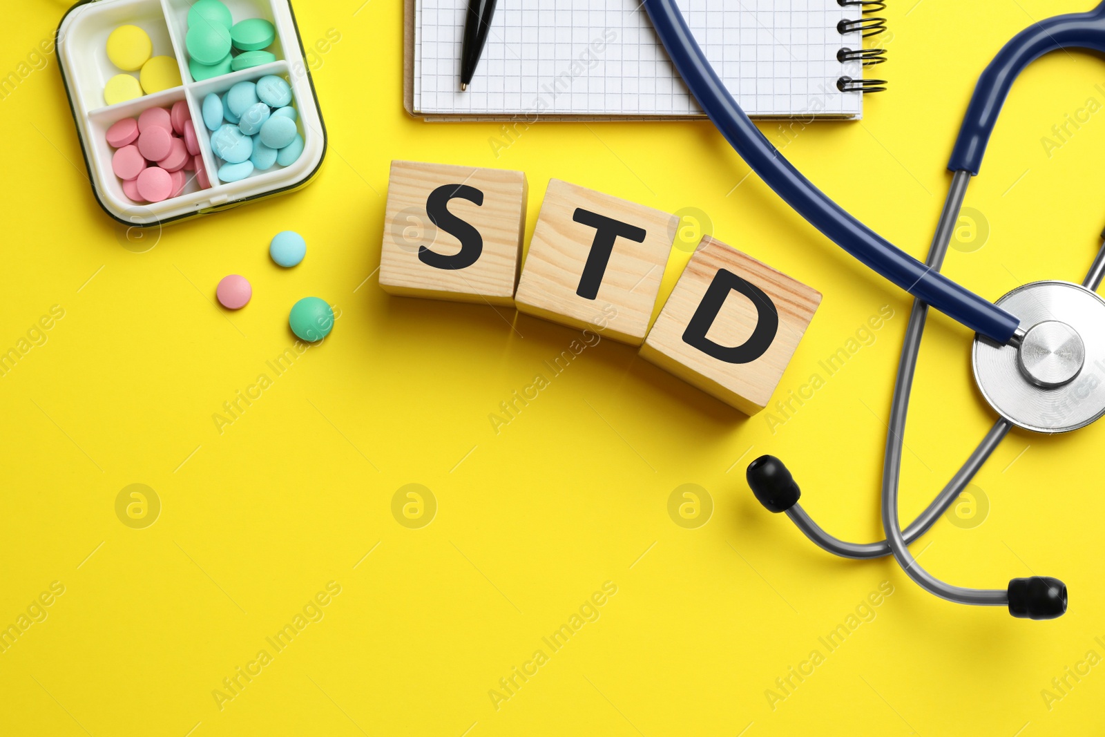 Photo of Flat lay composition with abbreviation STD, pills and stethoscope on yellow background