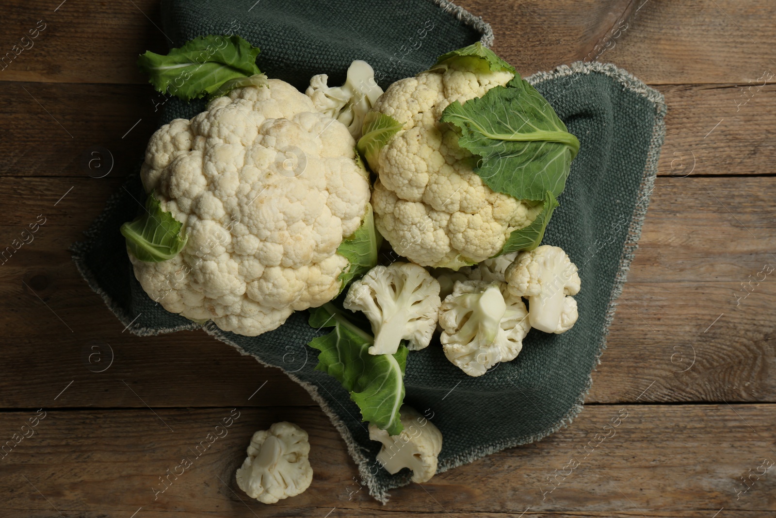 Photo of Cut and whole cauliflowers on wooden table, top view