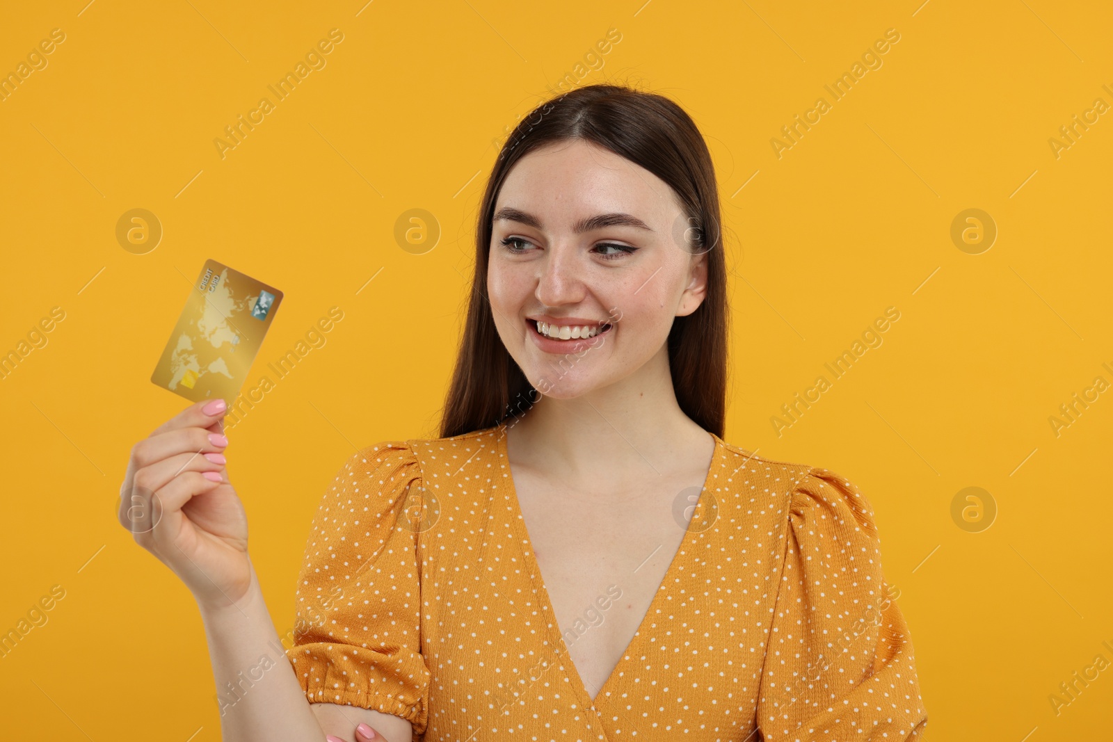 Photo of Happy woman with credit card on orange background