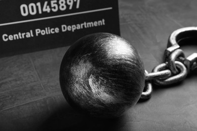Photo of Metal ball with chain and mugshot letter board on grey table, closeup
